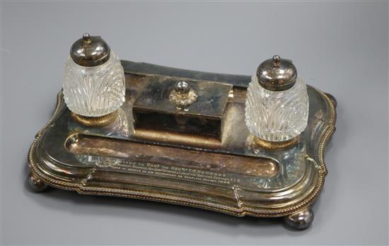 An early 20th century plated inkstand with two mounted glass wells and central lidded compartment 27.3cm wide, 11cm high